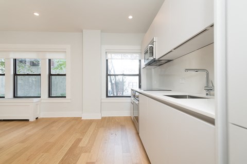 a kitchen with white cabinets and a sink and a window